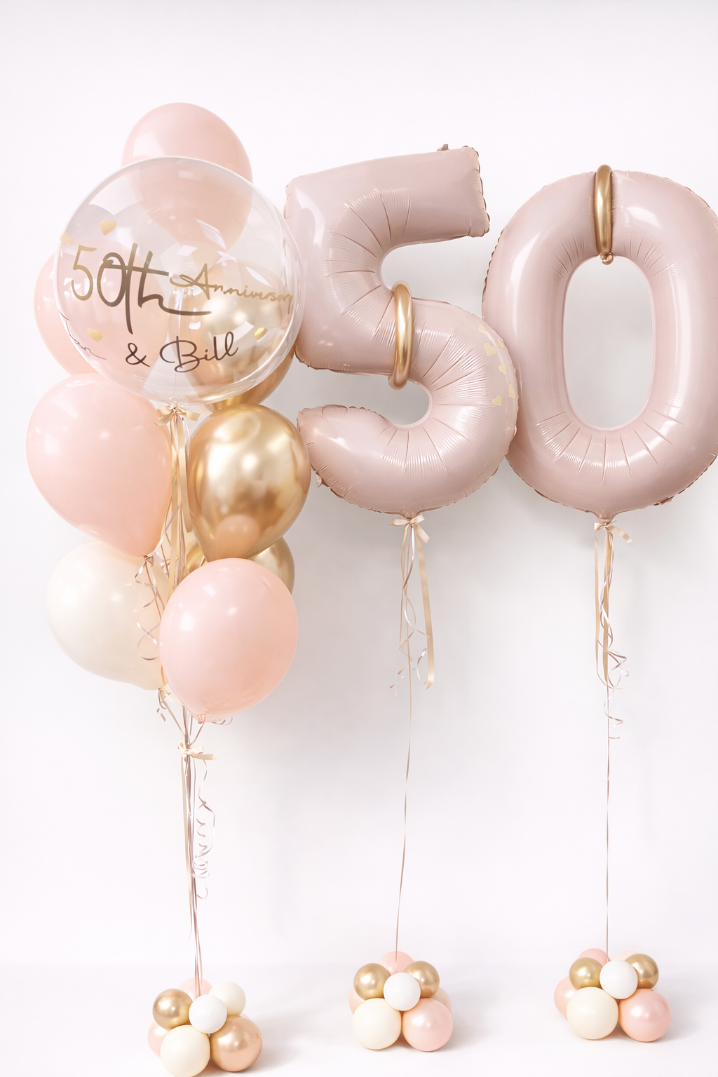 Elegant anniversary balloon arrangement with blush number balloons, gold accents, and clear custom bubble balloon