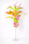 Tall balloon flower bouquet stand with green stems, pink, coral, yellow spiral blooms, and butterfly accents on a metal base