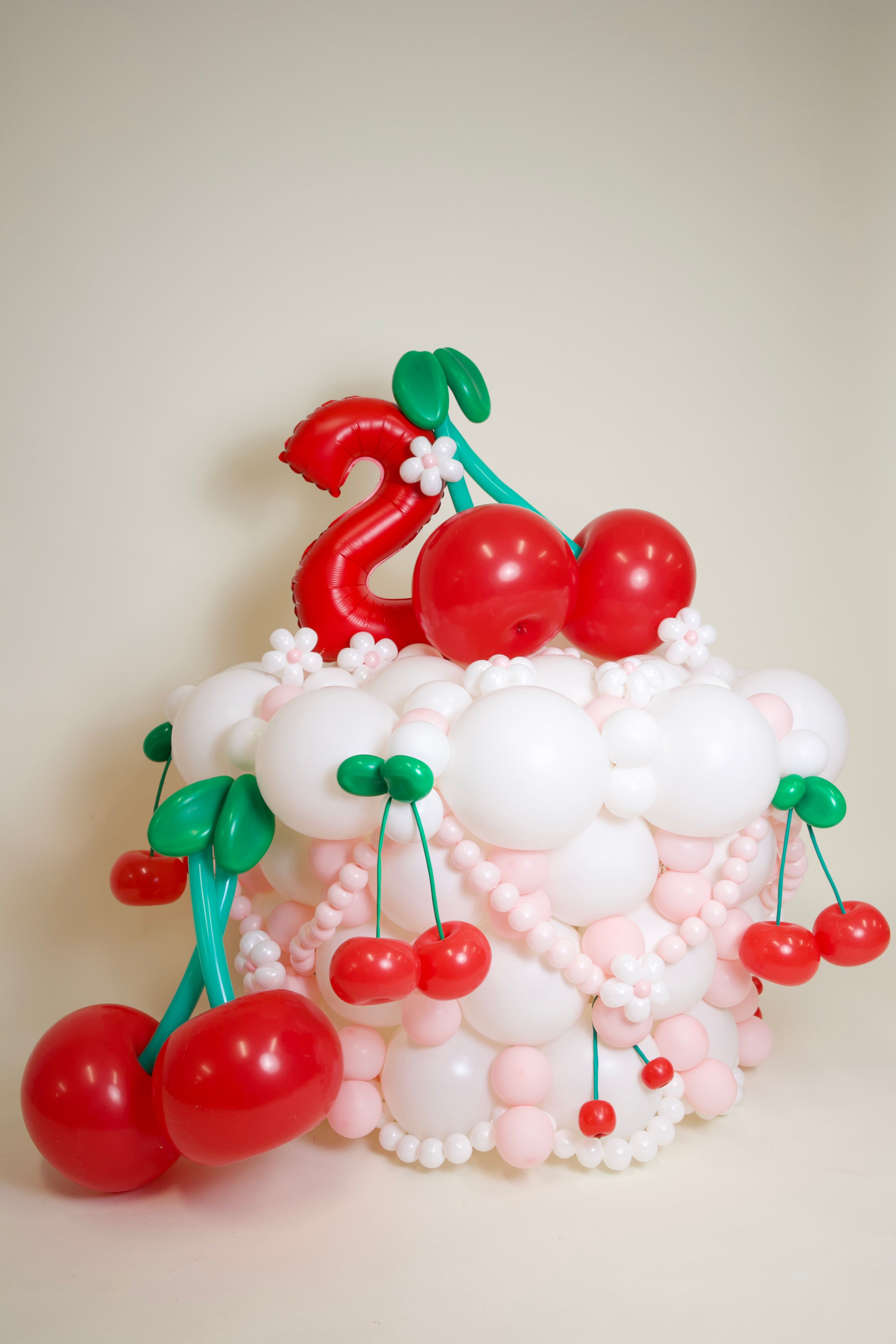 Balloon cake with cherries on a plain background