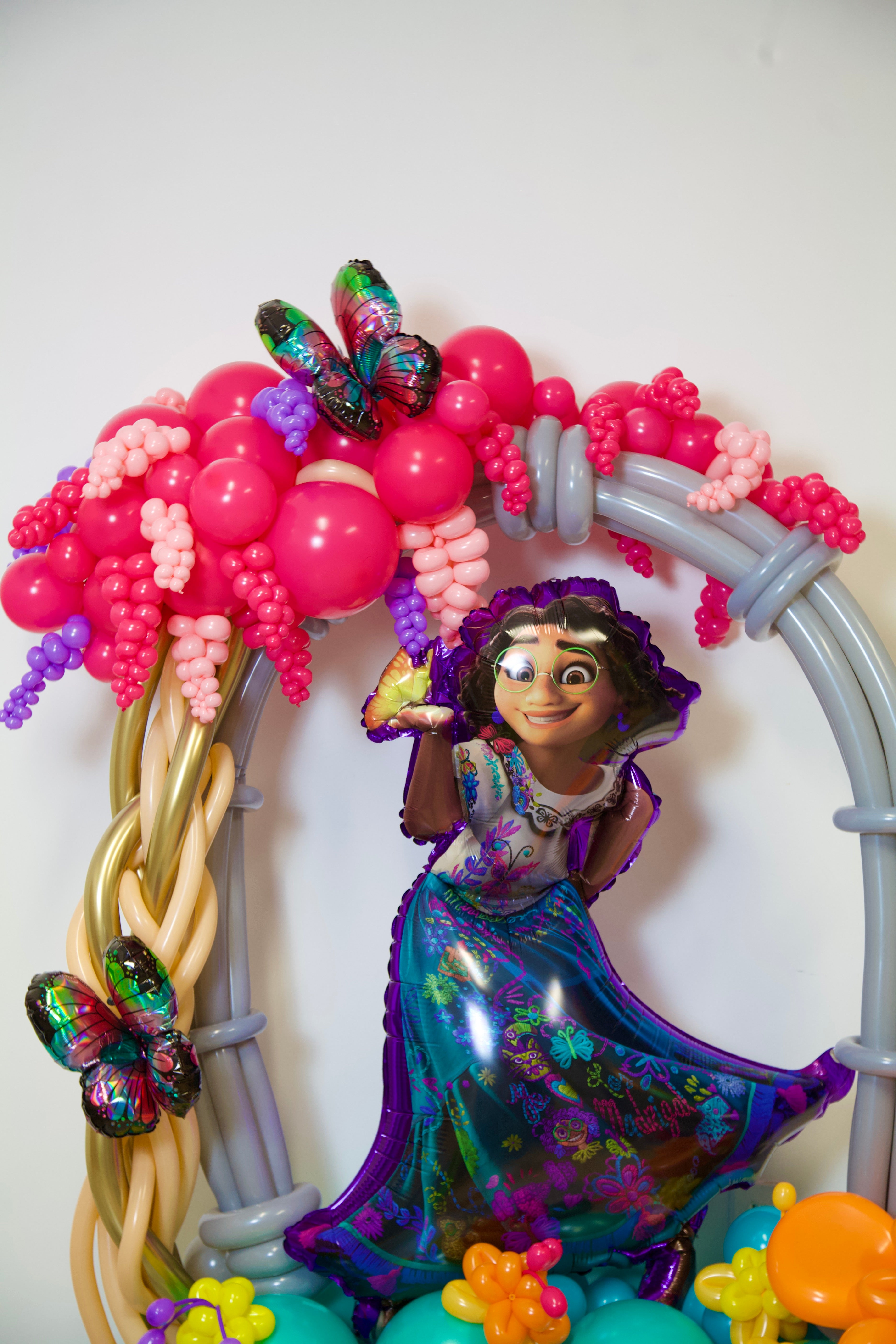Colorful balloon arch with a character figure and decorations on a white background