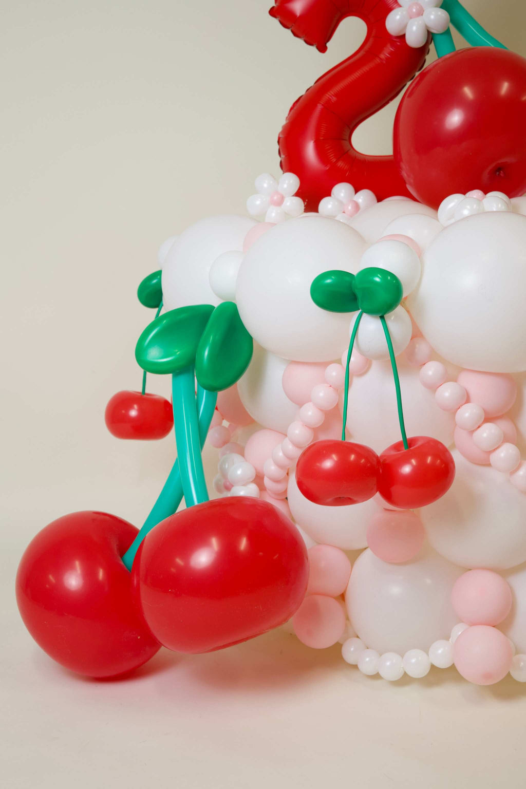 Two Sweet cherry birthday balloons with red cherries, blush balloon garland, pearl-style accents, and floral balloon details