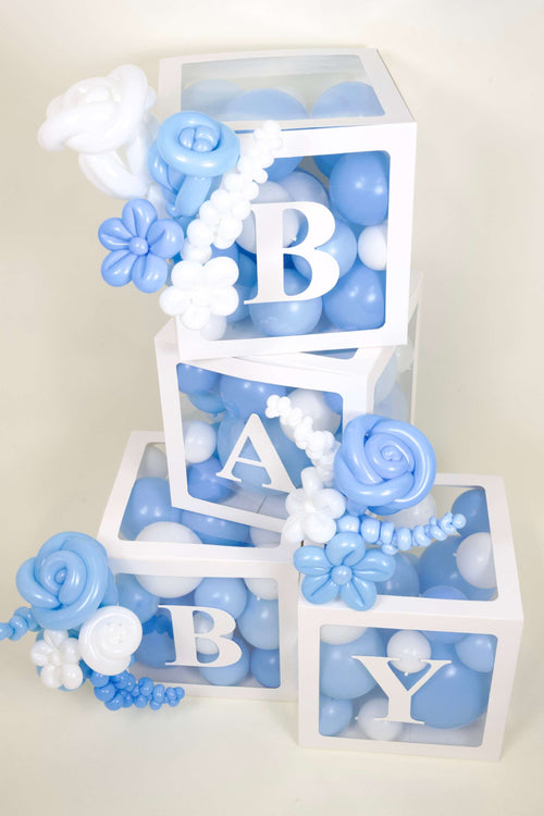Blue and white baby shower balloon box setup with floral accents