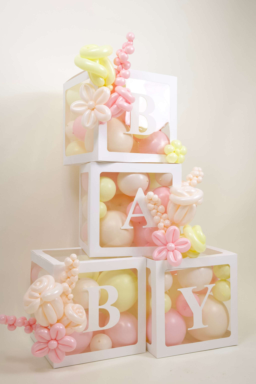 Baby shower balloon decor with BABY boxes, pastel balloon fill, soft floral accents, and cake table backdrop styling