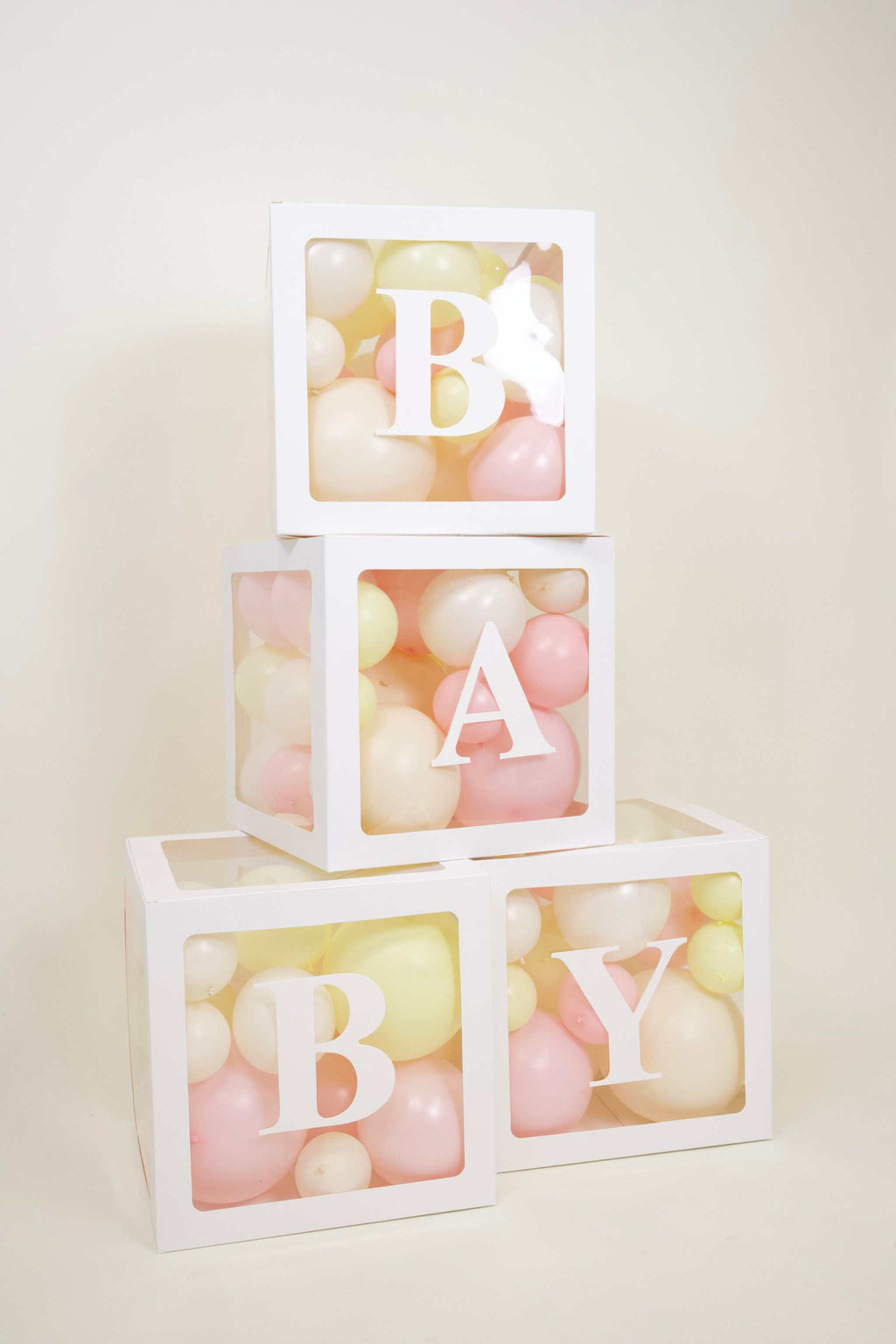 Pastel baby girl balloon boxes with white BABY display, blush balloons, buttercream details, and floral baby shower decor