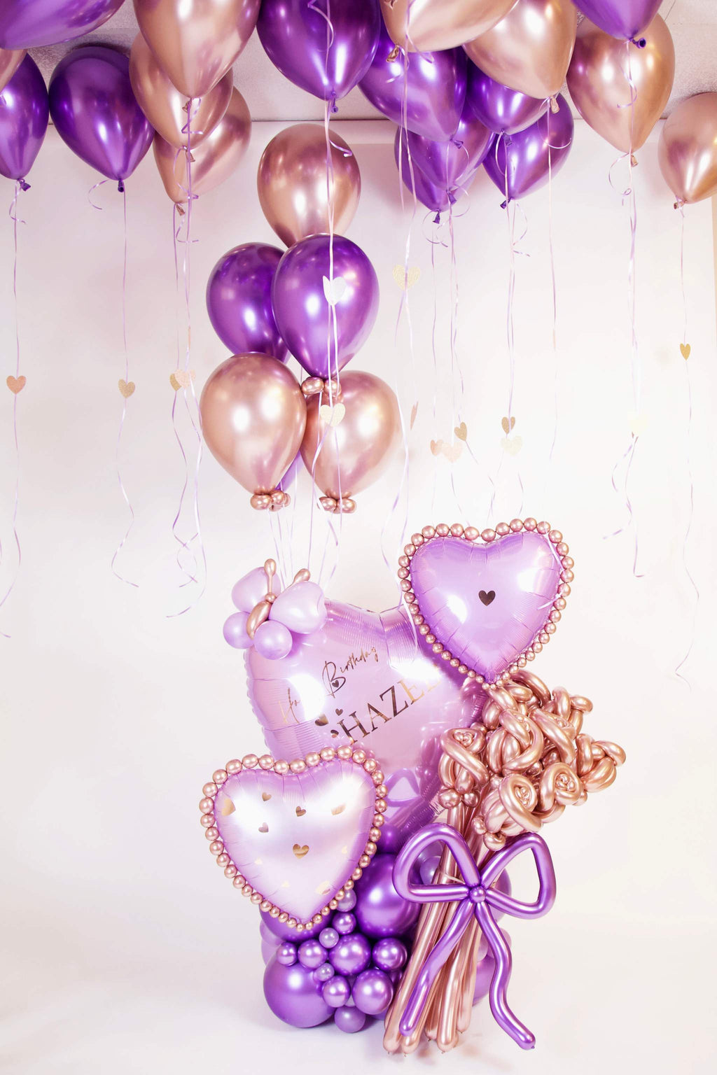 Purple and rose gold personalized birthday balloon arrangement with hearts, roses and custom message