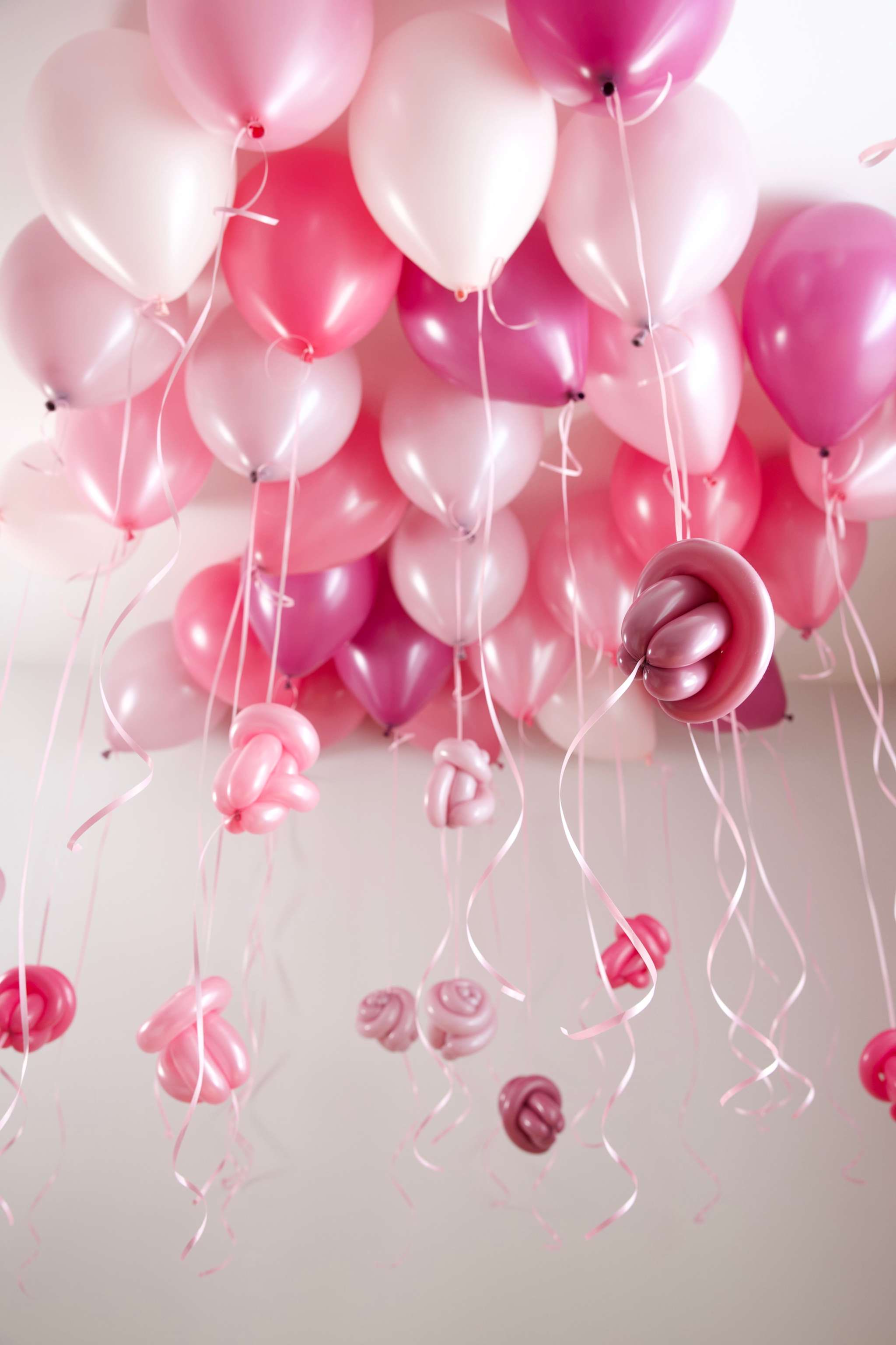 Pink and hot pink helium ceiling balloons with ribbons and twisted balloon flowers for a girls birthday party setup in Toronto