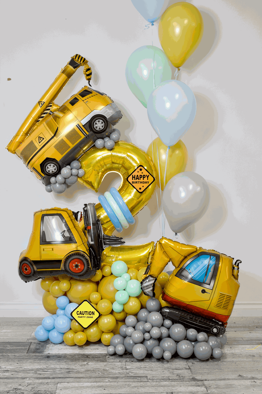 Construction birthday balloon arrangement with number balloon, construction vehicle balloons, and yellow blue balloon decor in Toronto