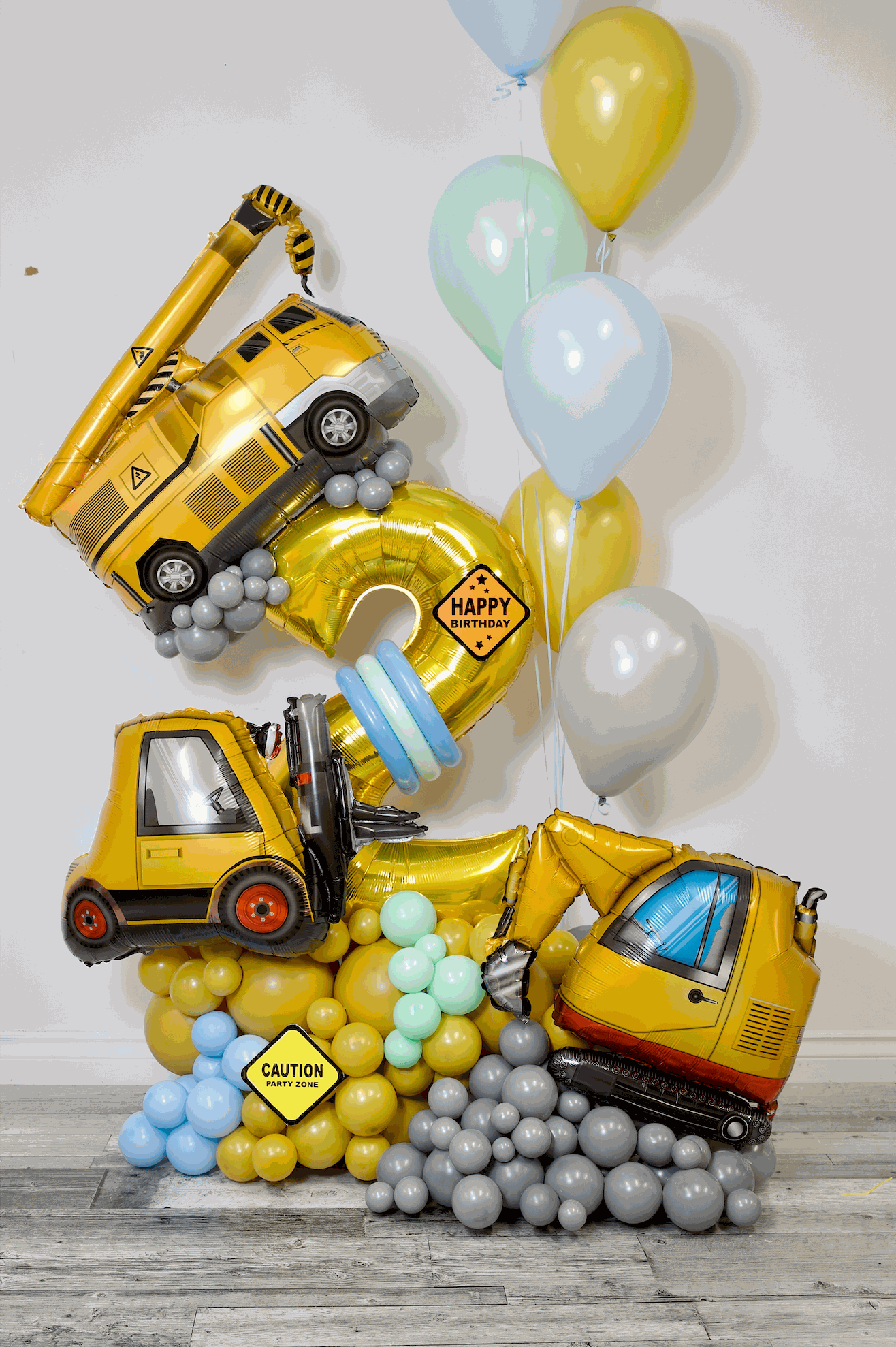 Construction birthday balloon arrangement with number balloon, construction vehicle balloons, and yellow blue balloon decor in Toronto
