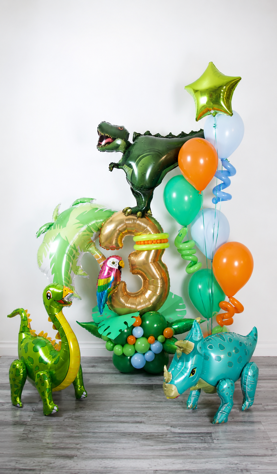 Dinosaur birthday balloon display with metallic age number, green jungle balloons, orange accents and dinosaur details