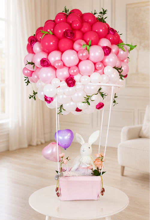 Blush Bunny Hot-Air Balloon gift arrangement with ombré pink and white balloons, floral accents, greenery, and a dressed bunny in a pink box