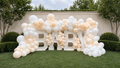 Ivory BABY marquee balloon installation with oversized illuminated letters and organic ivory, cream, and white balloons for luxury baby celebrations