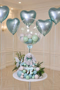 Personalized Little Miracle Bunny Bubble Balloon gift with plush bunny, clear bubble balloon, greenery, and satin bows in a woven basket for newborn celebrations