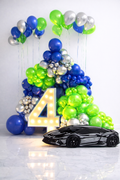 Luxury balloon arch with LED number 4 and car theme birthday setup in Toronto with light blue, neon green and silver balloons