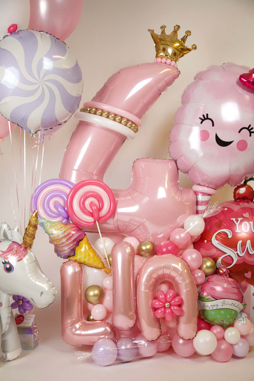Girls candyland birthday balloon display with pastel number balloon, unicorn balloon, cotton candy accent, lollipop details, and name balloons