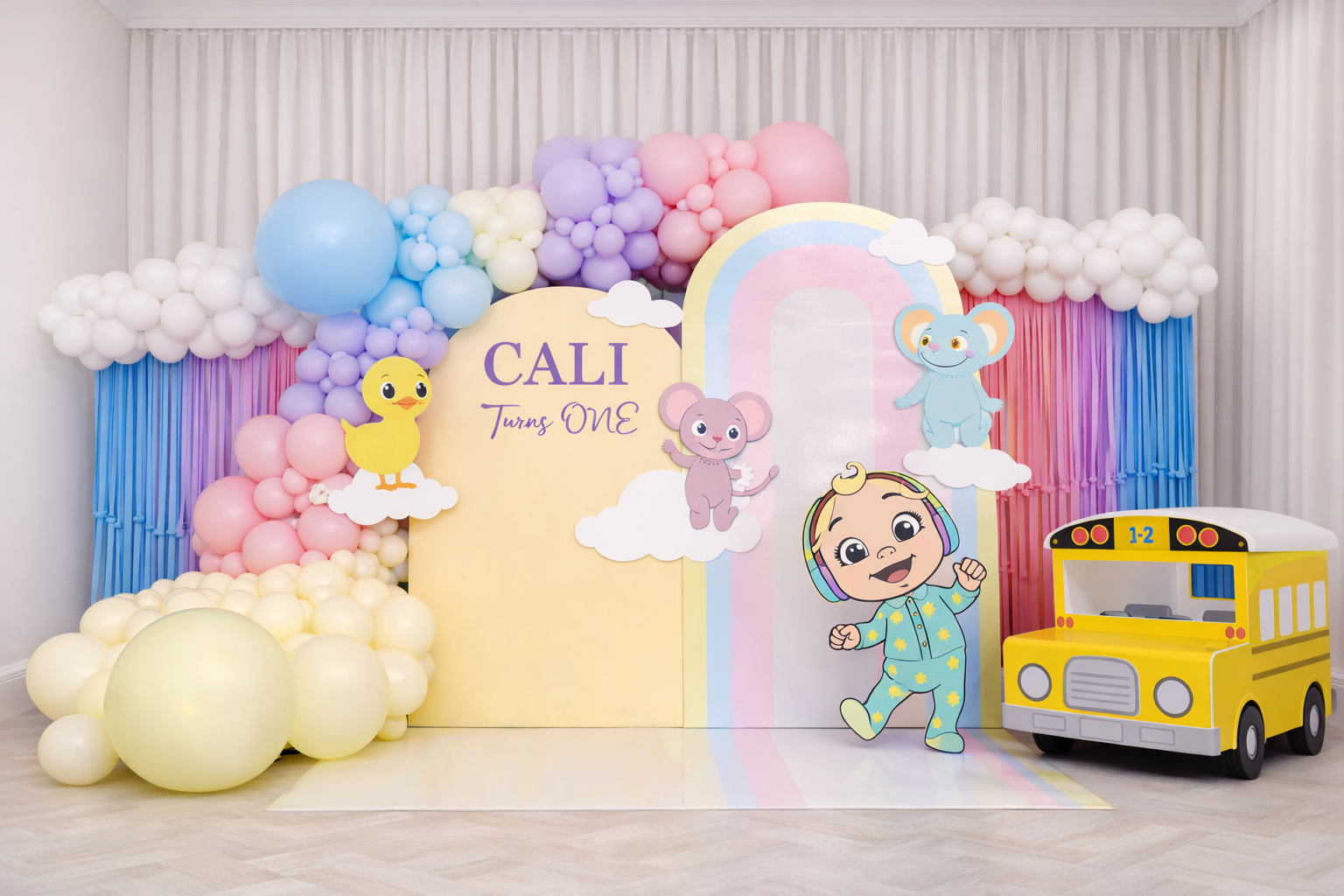 Pastel rainbow first birthday balloon setup with backdrop and kids party decor in Toronto