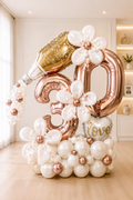 Rose gold 30th birthday balloon display with champagne bottle, pearl balloon flowers and personalized message