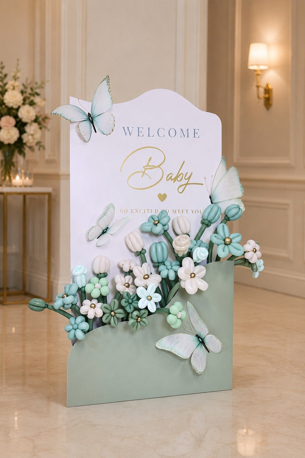Sculptural oversized envelope with handcrafted mint, sage, and ivory balloon flowers and welcome baby message for baby showers