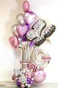 Sweet 16 luxury balloon display with oversized silver age numbers, chrome bouquet, butterfly accents and pearl floral base