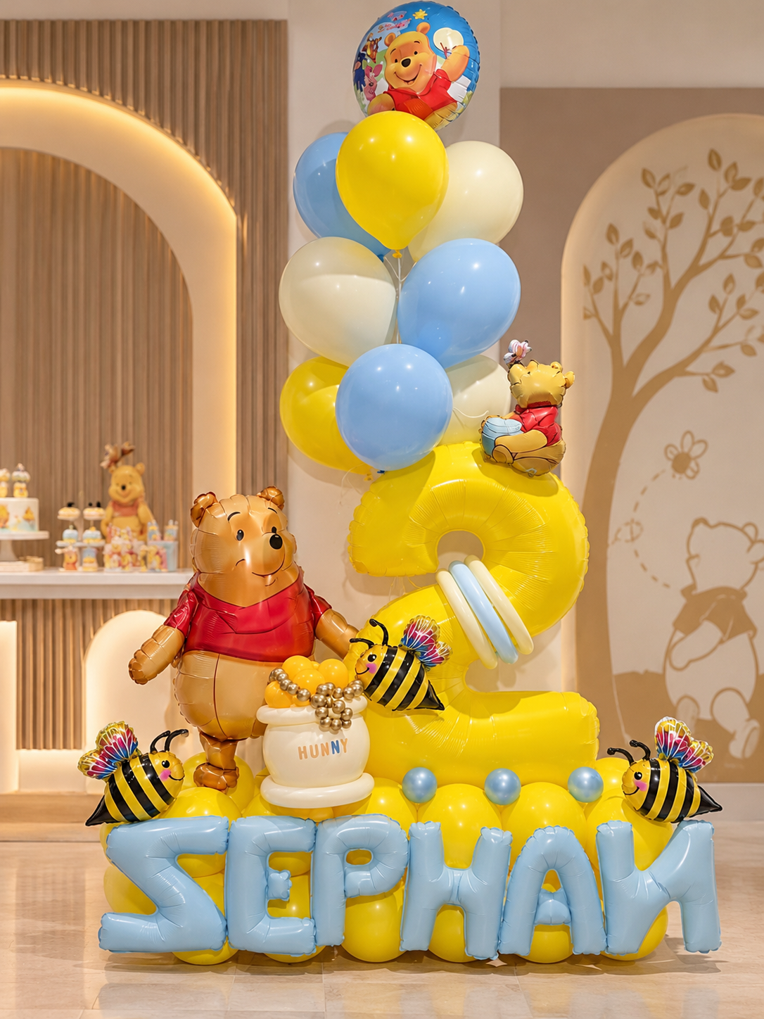 Winnie the Pooh birthday balloon arrangement with yellow number two and personalized blue foil name balloons